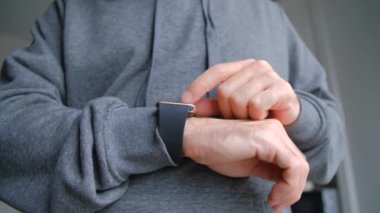 Akıllı saatler kullanıyor. 4K stok videosunda modern akıllı saat cihazının bildirilerini aşıran adam. Çevrimiçi iletişim için kol saati kullanıyor