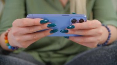 Cep telefonu ve hızlı internet bağlantısı olan bir kadın çevrimiçi video izliyor. Modern akıllı telefon kullanan ve kameralı bir kadın 4k 'lik yakın çekim videolarında yüksek kaliteli videolar izliyor.