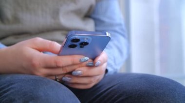 Cep telefonunda mesaj yazan bir kadın. Sosyal medya uygulaması üzerinden kadın iletişimi. 4K stok görüntülerinde iletişim ve eğlence için modern akıllı telefon aygıtı kullanan kişi