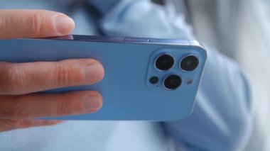 Cep telefonundan video izliyorum. 4K video klipte modern akıllı telefonu eğlence ve iletişim için kullanan kişi. Elinde yatay kameralı yeni moda cep telefonu tutan bir adam var.