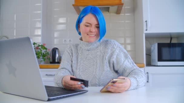幸せな白い女性がオンラインで購入 クレジットカードや携帯電話で自宅で青い髪のショッピングを染めた個々の白人女性 スマートフォンでインターネットストアで購入する陽気な人 — ストック動画