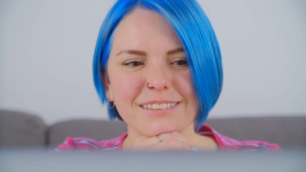 ロックダウンでオンラインで青の髪の学習を染めた幸せな白い女性 近くの4Kストックビデオのラップトップ画面から美しい若い女性の読書 かわいい百万人は インターネット上で遠くの学習を行う — ストック動画