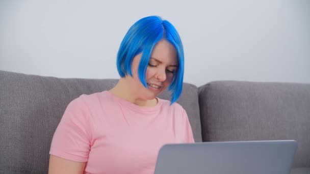 ラップトップコンピュータに入力した若い白人女性 染めの青い髪を持つ個々の白い女性は インターネットに接続された現代のノートブックでオンラインで動作します 自宅から遠く離れた仕事をしているフリーランスの人 — ストック動画