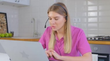 Dost canlısı internet destek operatörü neşeli bir gülümsemeyle kulaklıkla konuşuyor. Profesyonel yardım masası uzmanı müşteriyle çevrimiçi konuşuyor. Satış müdürü kadın 4K video 'da evden kilitli çalışıyor.