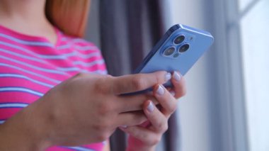 Stok videosunda modern cep telefonu kullanan bir kadın. Sosyal medya uygulamasında akıllı telefondan mesaj yazan genç kız