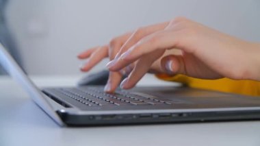 Klavyede yazan serbest çalışan kadın. Ofiste dizüstü bilgisayarda çalışan genç bir kadın. Modern dizüstü bilgisayar üzerine çalışan profesyonel kişi 4k yakın çekim videosunda