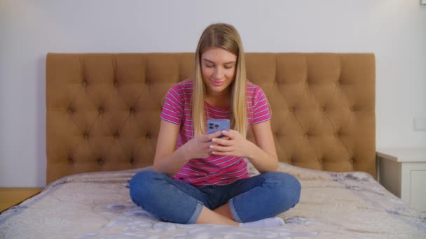 Happy White Female Typing Message Mobile Phone While Sitting Bed — Vídeo de Stock