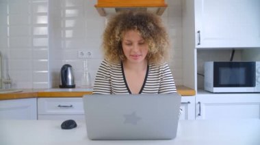 Evde çalışan serbest çalışan bir kadın. Güzel genç bir bayan, modern dizüstü bilgisayar ve hızlı internet bağlantısı üzerinde çalışıyor. 4K stok görüntülerinde dizüstü bilgisayar kullanan serbest çalışan kişi