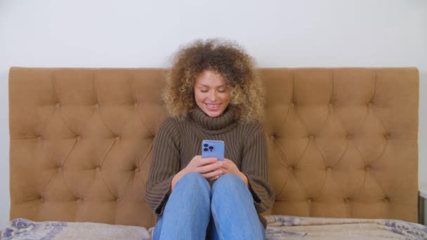 快乐的白人妇女使用手机进行交流 蓝色智能手机社交媒体应用程序上漂亮的卷曲女性在线输入消息 快乐的白种人在家里用现代手机 — 图库视频影像