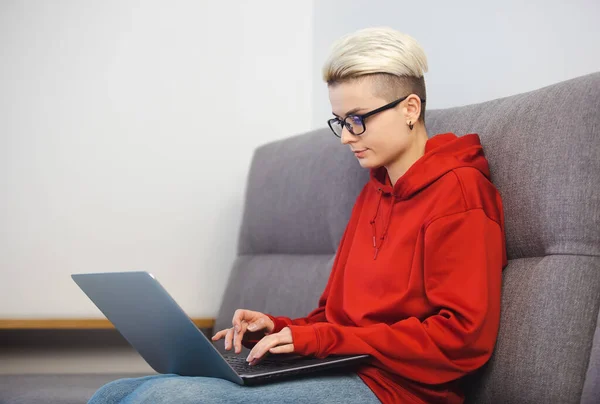 トムの男の子の女性はノートパソコンで働いている ノートパソコンのキーボードに短い髪の入力テキストを持つ起業家の実業家の女性は 自宅のロックダウンでソファに座っている 遠くの仕事をするフリーランスの人 — ストック写真