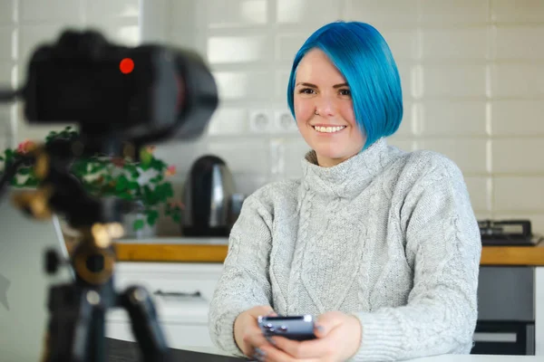 青い髪のビデオブロガーの女性がカメラで話しています 教育コースのためのビデオカメラについての陽気なオンライン教師の女性の話 Eラーニングとコーチングのコンセプト写真 — ストック写真