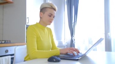 Bilgisayarda çalışan Tomboy kadın. Kilitleme sırasında evde dizüstü bilgisayarda yazı yazan boyalı kısa saçlı güzel bir bayan. Serbest çalışan kişi uzak çalışma için interneti kullanıyor