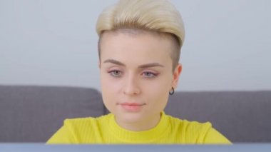 Evde dizüstü bilgisayarla çalışan kısa saçlı, serbest çalışan güzel bir kadının video portresi. Tom 'un erkek arkadaşı defter bilgisayarında uzak iş yapıyor. 4k görüntüde bilgisayar kullanan serbest yazar