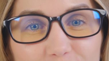 Genç sarışın kadının, kameraya doğru gülümseyen gözlüklü videosu. Güzel beyaz bir kadının neşeli bir yüz ifadesiyle konuştuğu yakın çekim videosu.