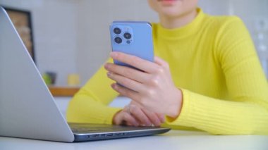 Serbest çalışan kadın internet ağı. Tecrit sırasında uzak iş ve iletişim için dizüstü bilgisayar ve modern cep telefonu kullanan serbest yazar. Genç bir kadın akıllı telefondan internette geziniyor.
