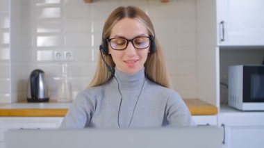 Dost canlısı çevrimiçi destek operatörü bilgisayardaki web kamerasından müşteriyle konuşuyor. Profesyonel yardım masası uzmanı kadın video görüşmesinde müşteriyle konuşuyor. Kulaklıklı neşeli sarışın kadın portresi