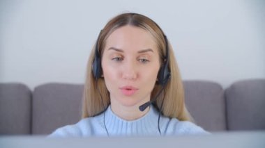 Çağrı merkezi operatörü kadın tecritte evden çalışıyor. İnternet destek uzmanı web kamerasından müşteriyle konuşuyor. Çevrimiçi öğretmen, 4k stok videosunda kulaklık ve web kamerasıyla öğrencilerle konuşuyor.