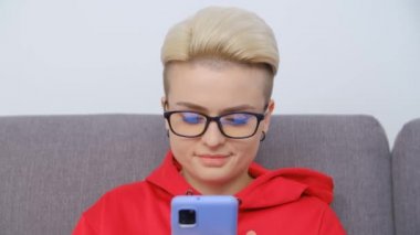 Gözlüklü, telefon kullanan güzel erkek fatma kadın. Modern akıllı telefon cihazında boyalı kısa saçlı, internet ve sosyal medyada gezinen çekici beyaz kadın portresi