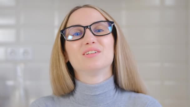 온라인 교사가 카메라로 말하는 안경을 아름다운 미소로 카메라에서 이야기하는 금발에 — 비디오