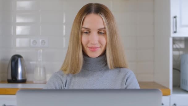 成年女学生在网上学习关闭 漂亮的金发女性在家里的笔记本电脑上工作 自由撰稿人在4K股票视频的笔记本电脑上做远程工作 — 图库视频影像