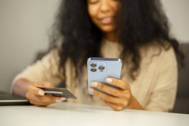İnternetten kredi kartıyla satın alan bir kadın. Siyah bir kadın internet mağazasından cep telefonu ve banka kartıyla alışveriş yapıyor. Akıllı telefon uygulaması ile online para transferi yapan kişi