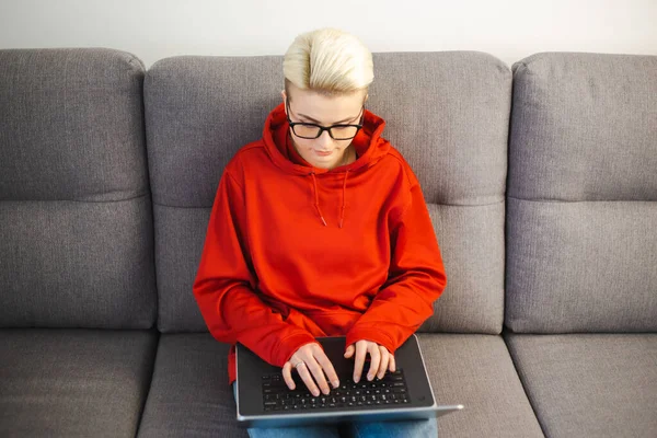 自由职业者是在家里用笔记本电脑工作的专业女性 企业家坐在客厅的沙发上 在笔记本电脑键盘上打字 自由撰稿人女性在网上做远程工作 — 图库照片