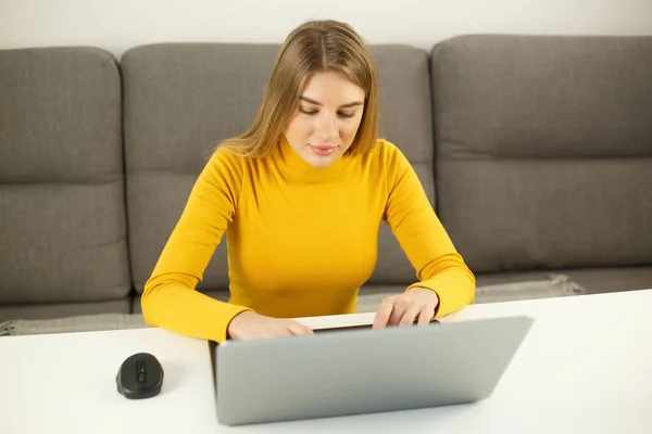漂亮的年轻女性在家里用笔记本电脑 迷人的金发女子在现代笔记本电脑键盘上打字 以自由撰稿人为重点的人在网上做远程关闭工作 — 图库照片