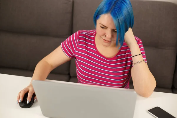 青い髪の若い白い女性がノートパソコンで働いています オンライン作業のための現代のノートPcを使用して色のボブの髪型とかわいい白人女性とロックダウン中の通信 — ストック写真