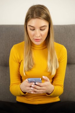 Telefonu kullanan güzel bir kadın. Genç sarışın kadın modern akıllı telefon uygulamasında mesaj yazıyor. Yeni cep telefonu aygıtında sosyal medya uygulaması üzerinden iletişim kuran çekici kişi