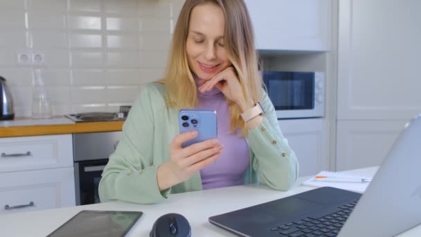 Evde Dizüstü Bilgisayarla Çalışırken Akıllı Telefon Kullanan Genç Bir Kadın — Stok video