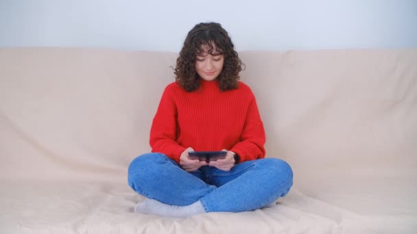 自宅でソファの上にデジタルタブレットを使用して若い女性 — ストック動画