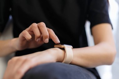 Evde akıllı saatler kullanan bir kadın. Genç beyaz kadın, modern kol saati hakkında bilgi topluyor. Akıllı saat aygıtında mesajları okuyan kişi