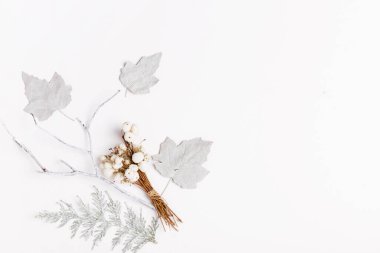 Minimalist Noel kompozisyonu beyaz yapraklardan ve beyaz arka planda böğürtlenlerden yapılmış parlak renklerde. Noel, kış, yeni yıl konsepti.