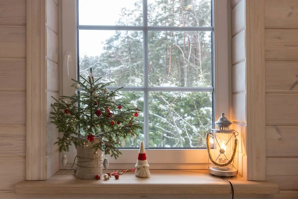 Χριστουγεννιάτικο φανάρι, Χριστουγεννιάτικο νάνο, χριστουγεννιάτικο δέντρο και κόκκινη διακόσμηση στο παράθυρο ενός ξύλινου σπιτιού — Φωτογραφία Αρχείου