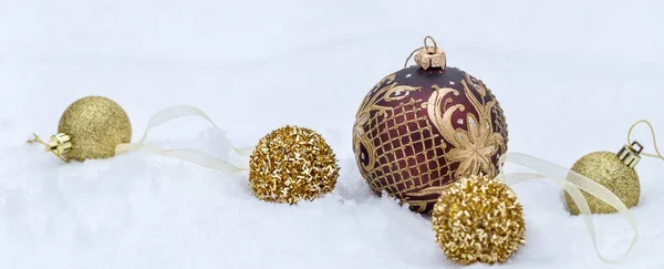 Zlaté vánoční koule na sněhu pozadí, vánoční prapor — Stock fotografie