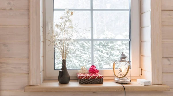 Ρομαντικό παράθυρο σε ένα λευκό ξύλινο σπίτι με θέα τον χειμερινό κήπο, Σκανδιναβικό στυλ. Φανός, κεριά και καρδιά στο περβάζι του παραθύρου. — Φωτογραφία Αρχείου