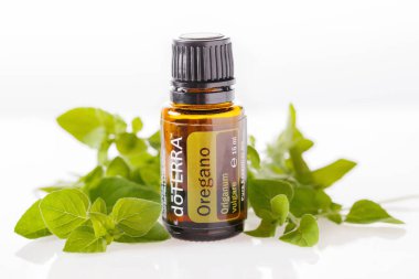 Riga, Latvia - July 20, 2022: doTERRA essential oil of oregano on a background of fresh sprigs of oregano, quality essential oils.