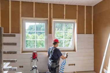 İnşaat işçisi termal olarak eko ahşap çerçeve çevre dostu evleri yalıtıyor. Sıkışmış ısı kenevir lifini yalıtıyor ve beyaz ahşap tahta