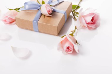 Hediye kutusu ve beyaz arka planda pembe güller. Uzayı kopyala Yukarıdan bak. Düz tasarım.