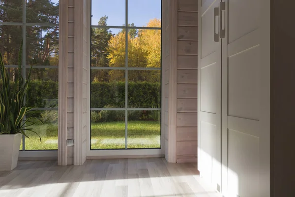 Bright interior of the room in wooden house with a large window overlooking the autumn courtyard. Golden autumn landscape in white window. Home and garden, fall concept. Plant Sansevieria trifasciata