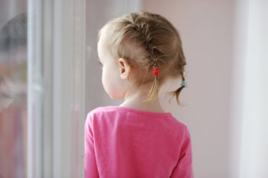 Adorable little girl by the window clipart