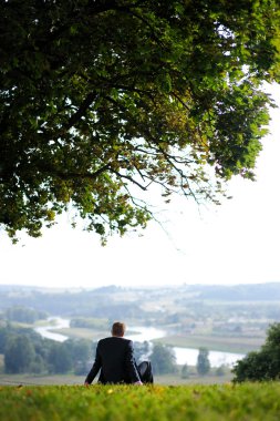 hombre de negocios descansando bajo un roble