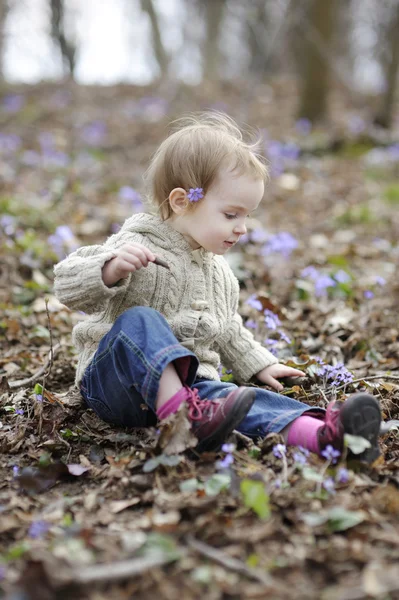 Kleines Mädchen berührt erste Frühlingsblumen — Stockfoto