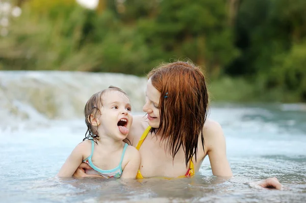 Menina adorável e sua mãe em uma praia — Fotografia de Stock
