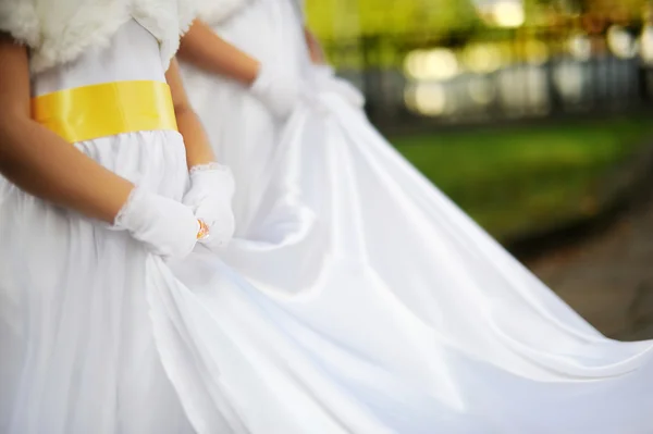 Подружки невесты, держащие свадебное платье невесты — стоковое фото