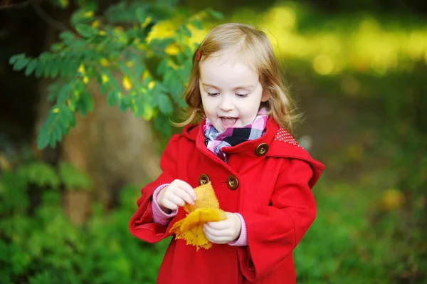 Little girl in bright red coat at autumn — Stock Photo, Image