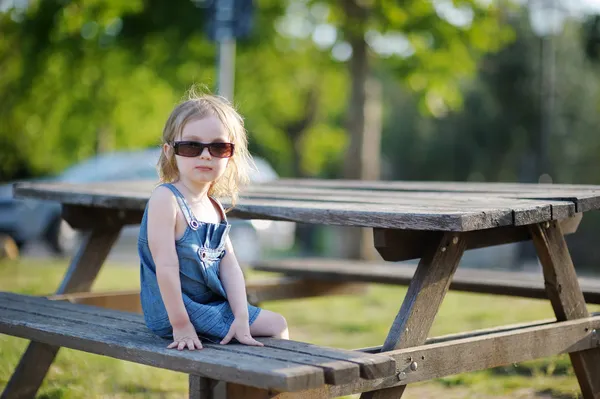 Adorável menina sentada em um banco — Fotografia de Stock