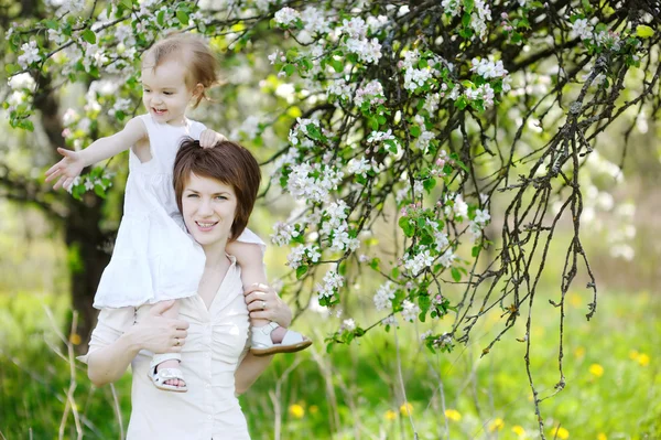 Mladá matka a její dcera v kvetoucí stromy — Stock fotografie