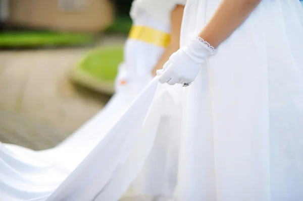 Bridesmaids holding bride's wedding dress — Stock Photo, Image