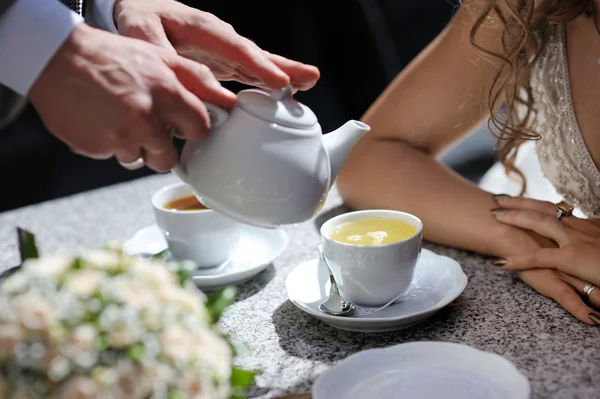 De bruid en bruidegom de handen op de tafel van de thee — Stockfoto